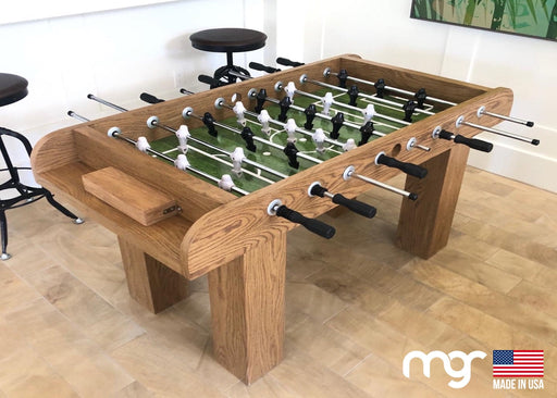 Wooden foosball table with MG brand logo in a room setting