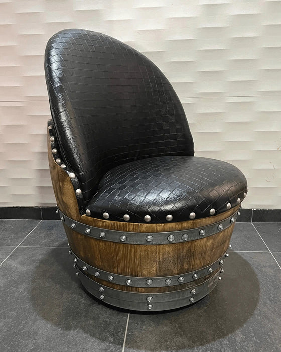 Chair made from a repurposed wine barrel with black leather seat against a neutral wall.