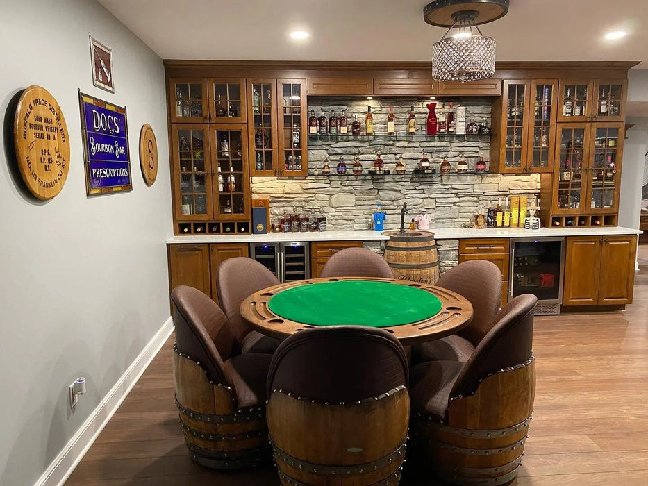 Game room with a poker table and barrel chairs, featuring a bar area in the background.