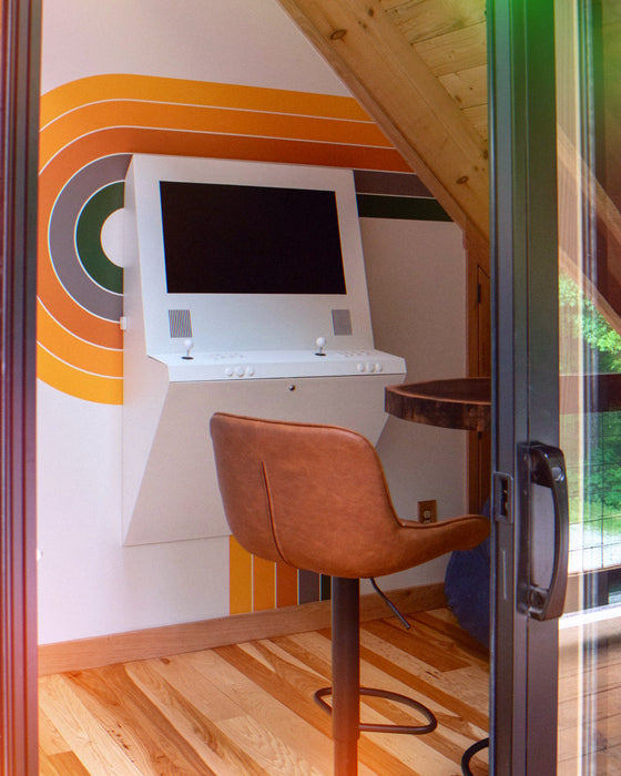 Modern home office with a wall-mounted TV, brown chair, and colorful wall design.