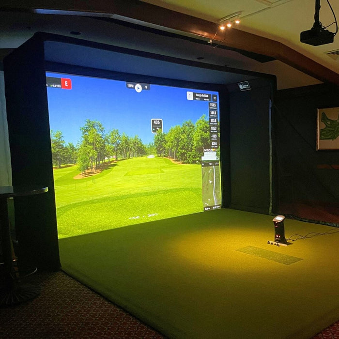 Indoor golf simulator setup with screen displaying a golf course.