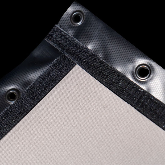 Close-up of a corner with black fabric trim and metal grommets on a gray background