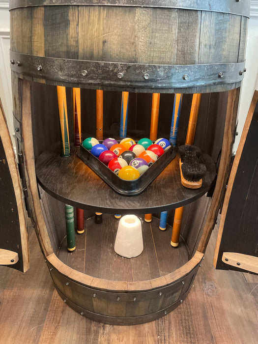 Wooden barrel with pool balls and cues on a wooden floor