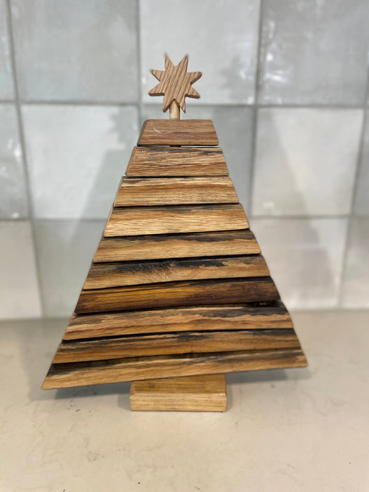 Wooden Christmas tree decoration with a star on top against a tiled wall background