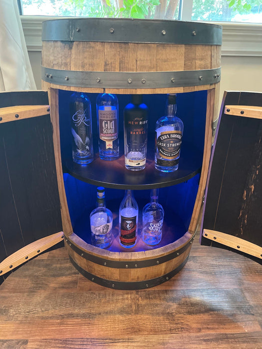 Wooden barrel with blue interior displaying various bottles of alcohol.
