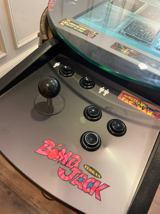 Close-up of an arcade machine with 'Bomb Jack' branding on a wooden floor.