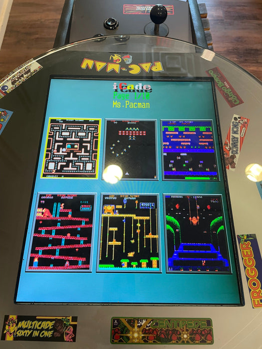 Vintage Pac-Man arcade machine with colorful display on a wooden floor.