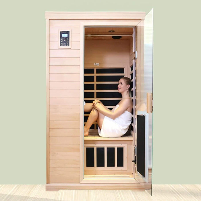Woman sitting inside a wooden infrared sauna with a light green wall.