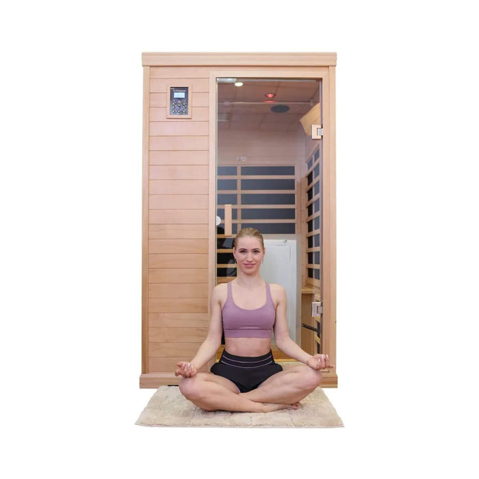 Woman sitting in front of a wooden infrared sauna on a white background