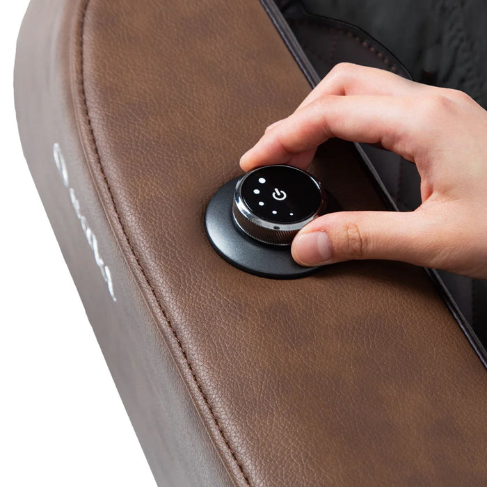 Hand pressing a control knob on a brown leather chair.