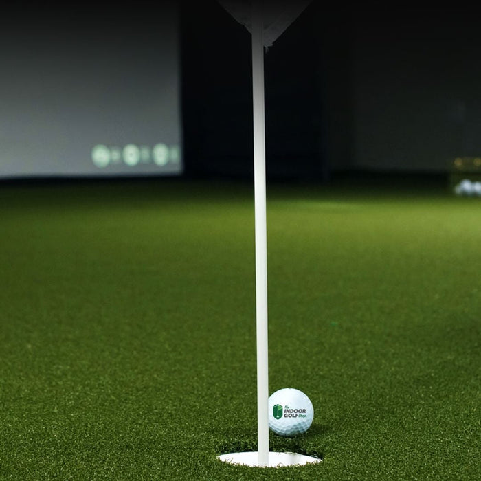 Golf ball on a tee with a flagstick in a virtual golf simulation setup