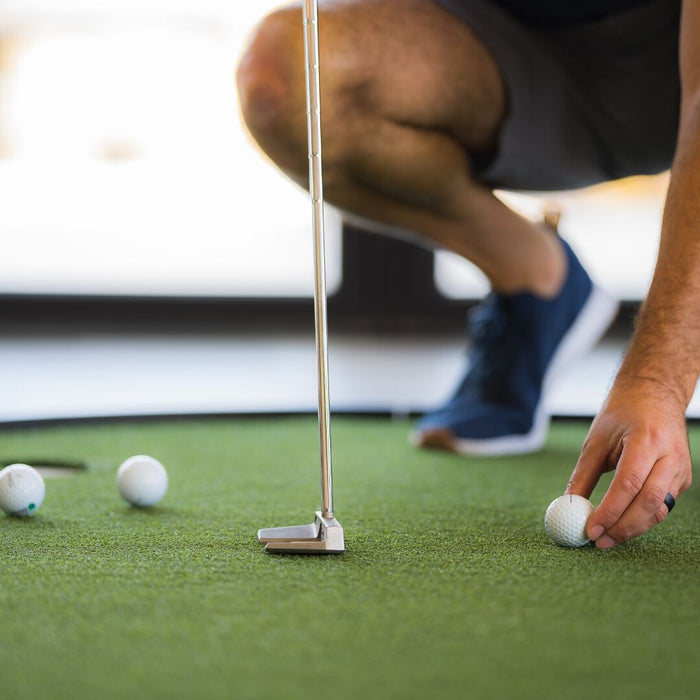 Person playing mini golf on a green surface with a blurred background
