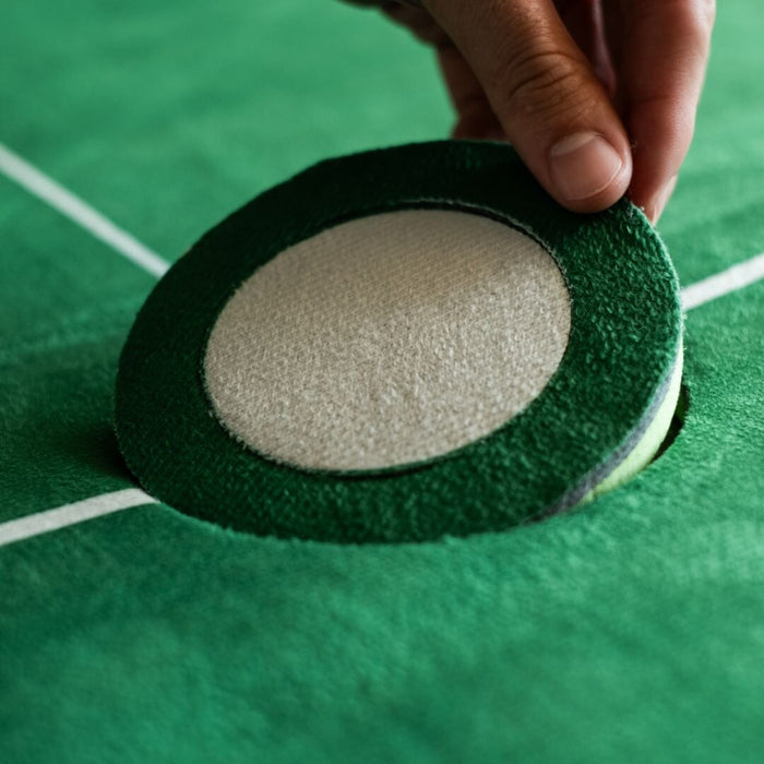 Close-up of a hand holding a green and white object on a green surface