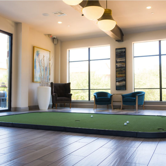 Indoor putting green with chairs and large windows in the background