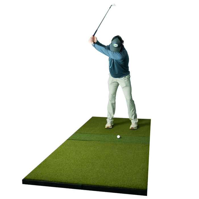 Person practicing golf swings on a green mat with a white background