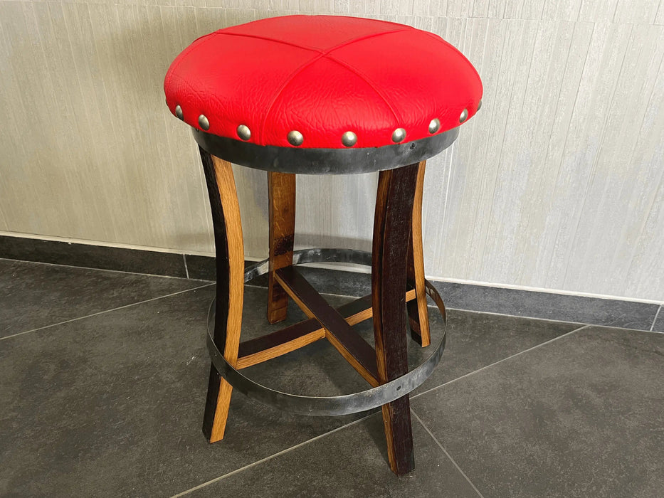 Red bar stool with wooden legs on a tiled floor against a neutral wall.