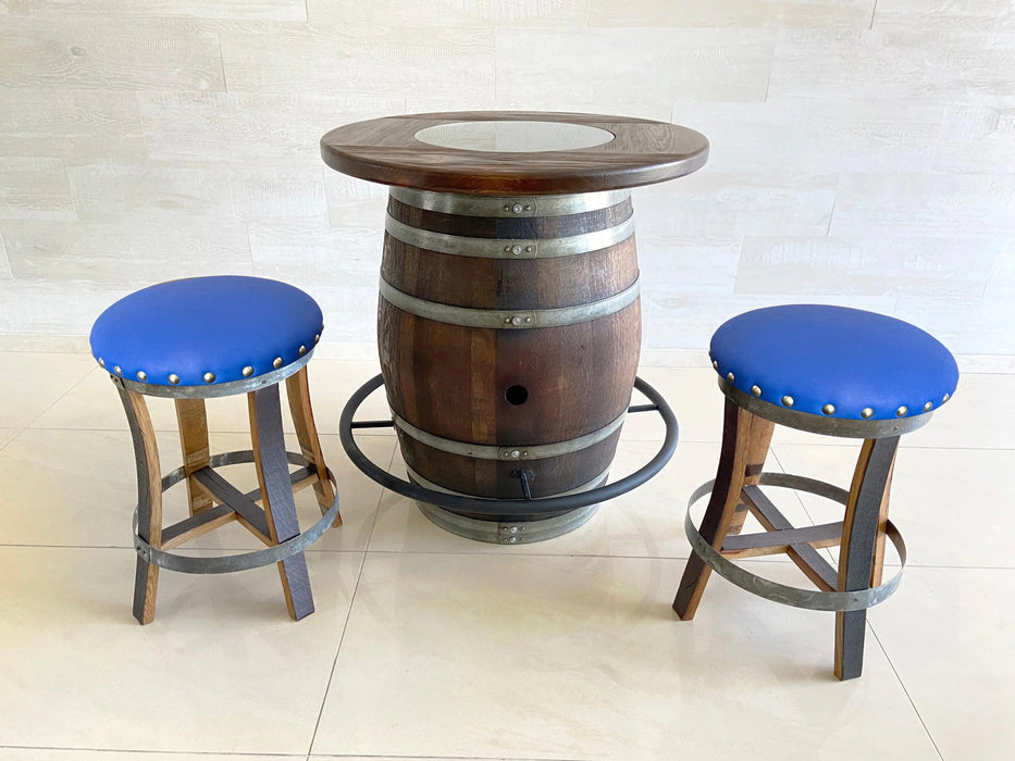 Barrel table with two blue cushioned stools on a light tiled floor.