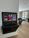 Black entertainment console with screen displaying a video game in a room with wooden flooring.