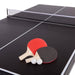 Two ping pong paddles with red and black一面 and two white balls on a black table tennis table.