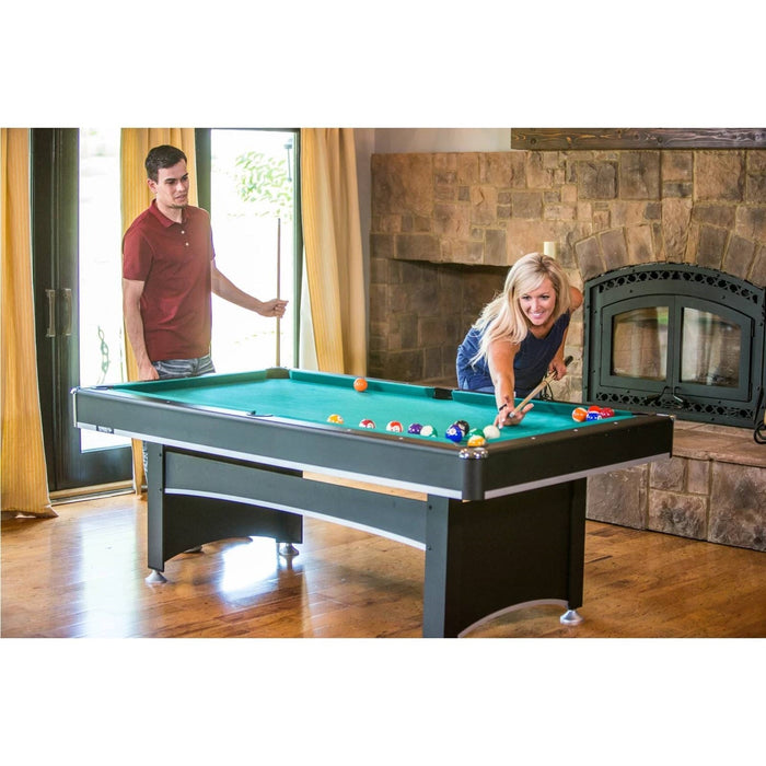 Two people playing pool in a room with a fireplace.