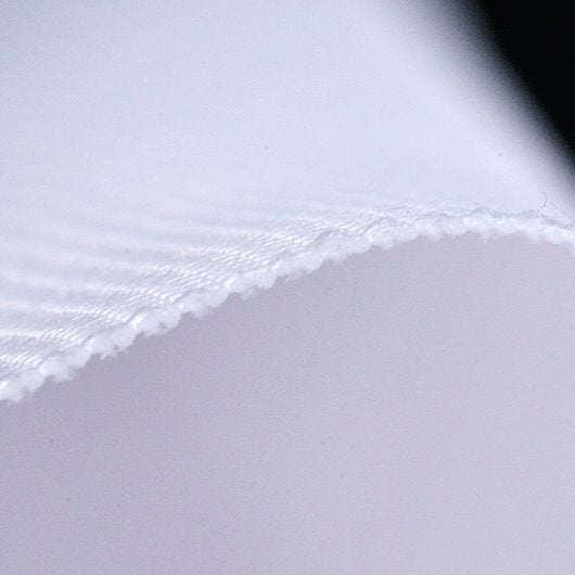 Close-up of white fabric with a visible seam on a light gray background