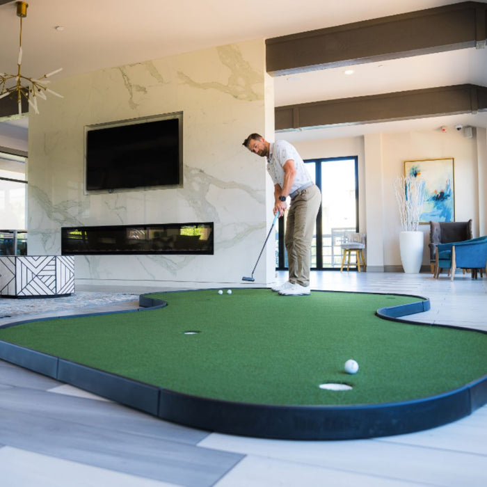 Man playing indoor putting green in a modern living room.
