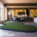 Person playing mini golf indoors in a modern living room setting.