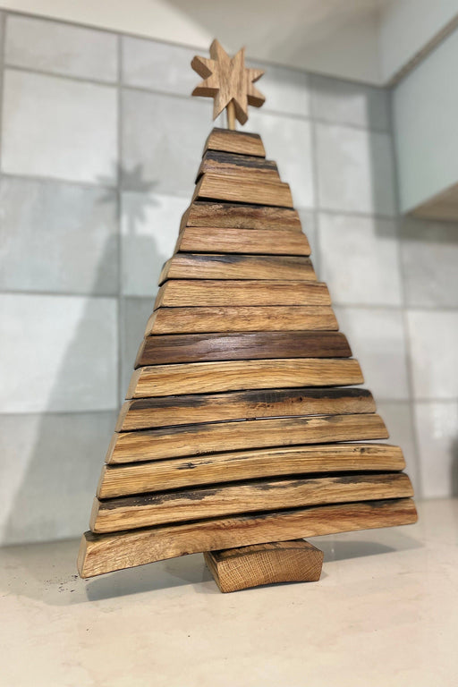 Wooden Christmas tree decoration with a star on top against a tiled wall.