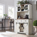 White bar cabinet with wine bottles and glasses in a home setting
