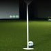 Golf ball on a tee with a flagstick in a virtual golf simulation setup