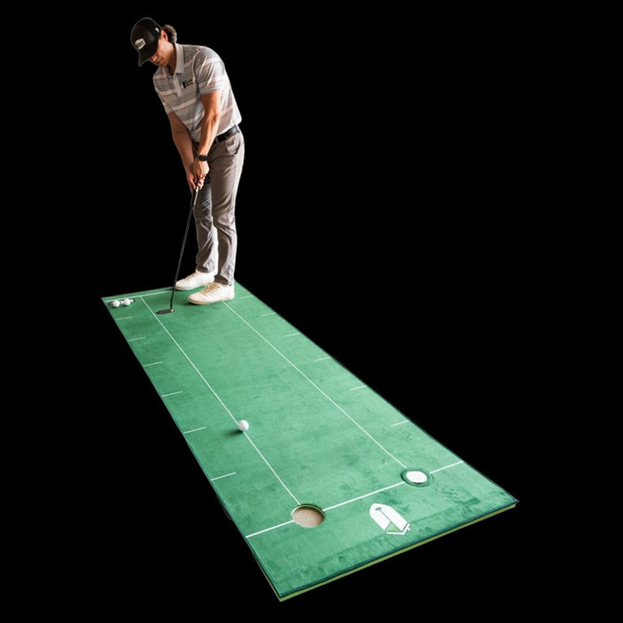 Person practicing golf on a green mat with a black background