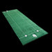 Green golf practice mat with white lines and golf accessories on a black background